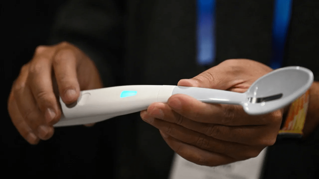 A person holding a Kirin Electric Salt Spoon, a futuristic kitchen gadget designed to enhance flavor without added sodium, featuring a white design and a glowing blue indicator.