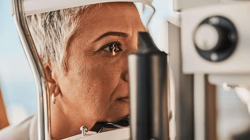 Close-up of a woman undergoing an eye examination, focusing on her eye in a specialized examination device.