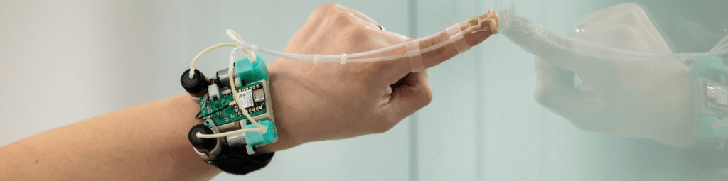 A hand wearing a skin-attached haptic device with sensors and actuators, designed for delivering tactile feedback in virtual reality.