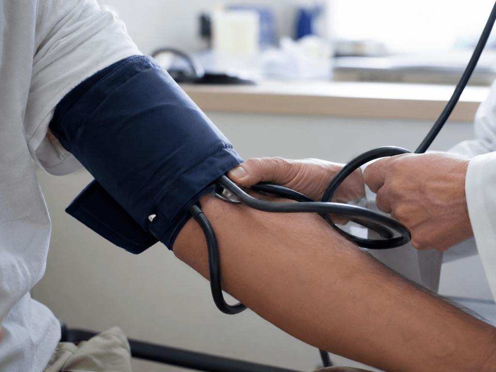 Healthcare professional measuring a patient’s blood pressure with a cuff and stethoscope