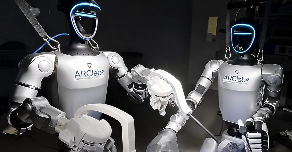 Two humanoid robots holding laparoscopic instruments during a preclinical gallbladder removal procedure.