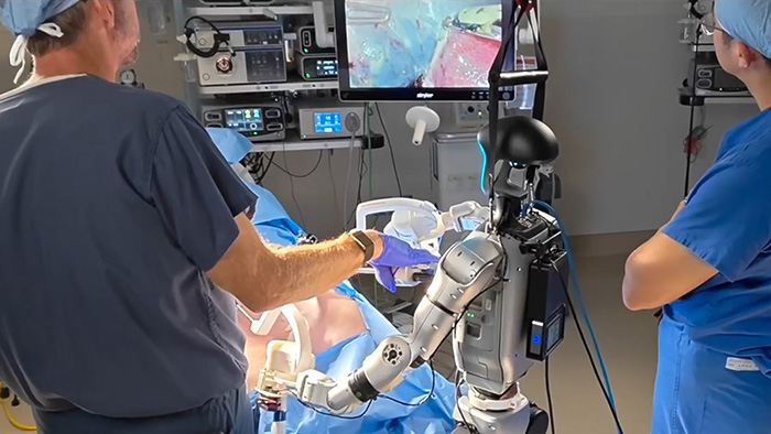 Human surgeon and humanoid robot working together during a preclinical gallbladder removal procedure in an operating room.